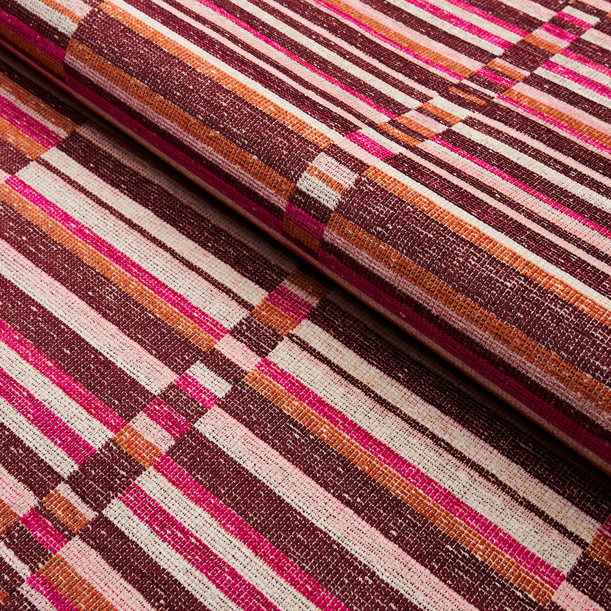 Close-up of multicolor striped woven fabric in pink, magenta, orange, brown and cream, rolled at the edge.