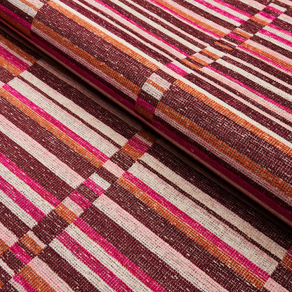 Close-up of multicolor striped woven fabric in pink, magenta, orange, brown and cream, rolled at the edge.
