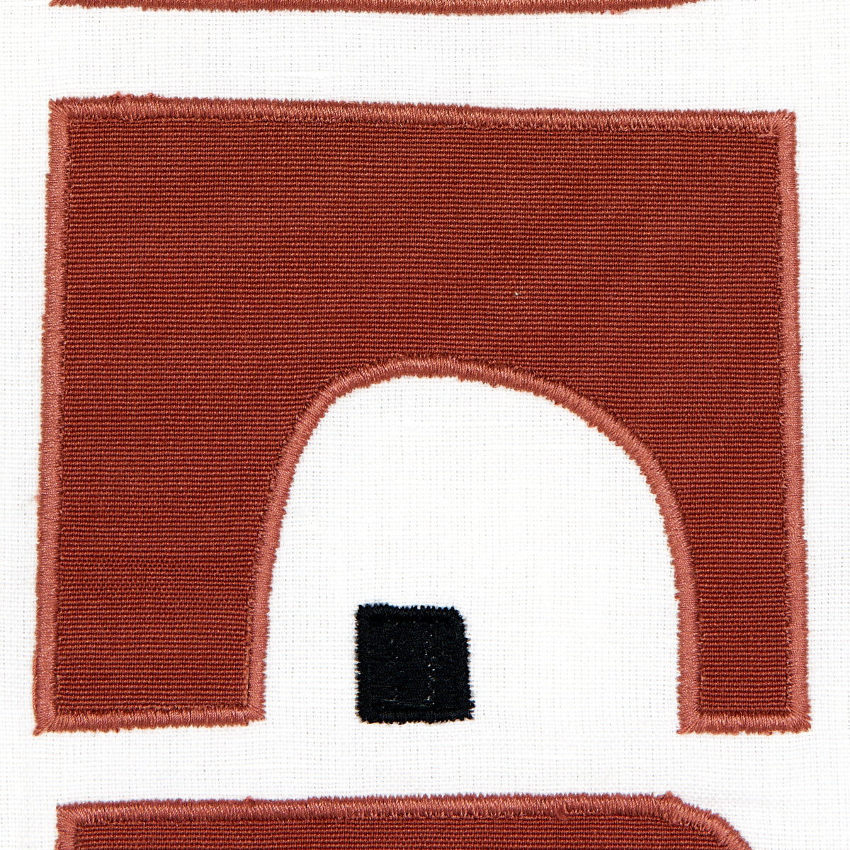 Red burgundy arch embroidery patch on white fabric; arched doorway shape with a small black square inset.