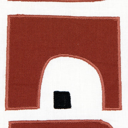 Red burgundy arch embroidery patch on white fabric; arched doorway shape with a small black square inset.