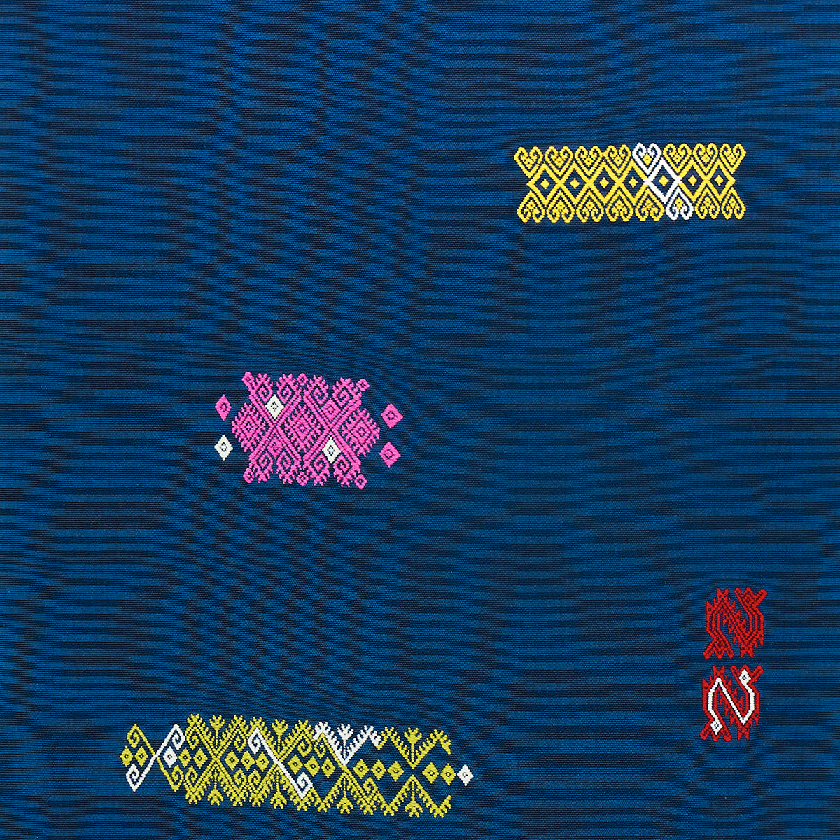 Blue textile with yellow diamond top-right, pink diamond cluster center-left, yellow-white zigzag bottom-left, red emblem right