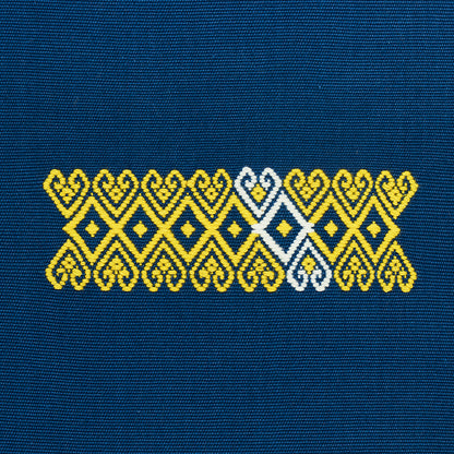 Yellow and white geometric embroidery band with diamond motifs on blue denim fabric.