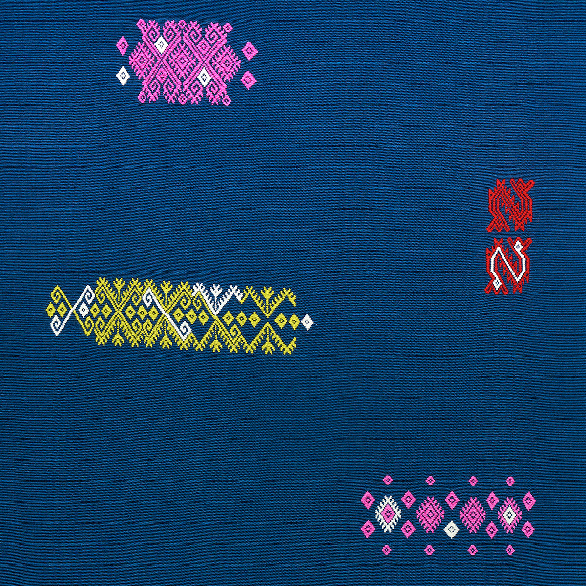 Blue fabric with multicolored geometric embroidery: pink diamond cluster, yellow/white band, and red vertical motif.
