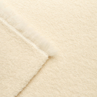 Cream plush blanket & fluffy fringe along folded edge, soft wooly texture.