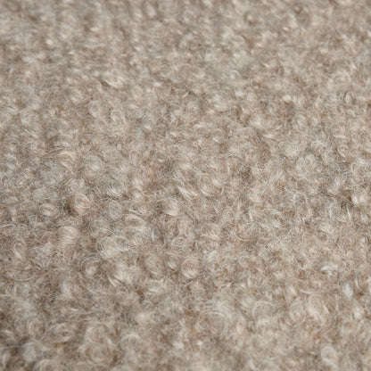 Beige boucle wool fabric close-up with soft curly fibers and cozy textured surface.