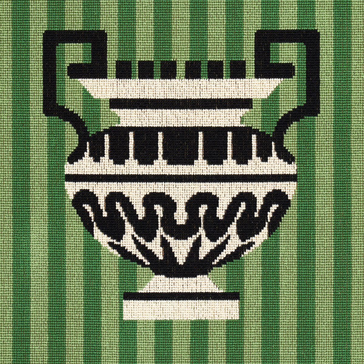 Decorative black-and-white urn with handles on a green striped woven textile.