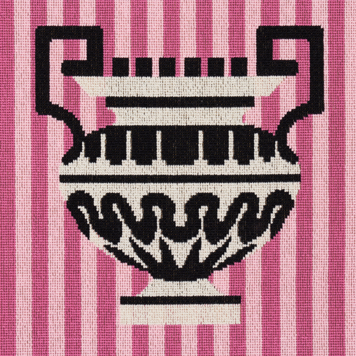 Knitted fabric with a black and white ornate urn motif on pink striped background.