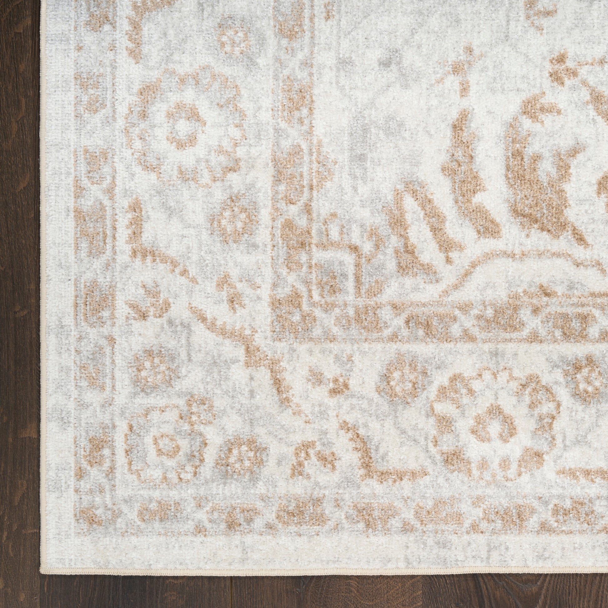 Ivory, cream and tan oriental rug with distressed floral medallion pattern on wood floor.