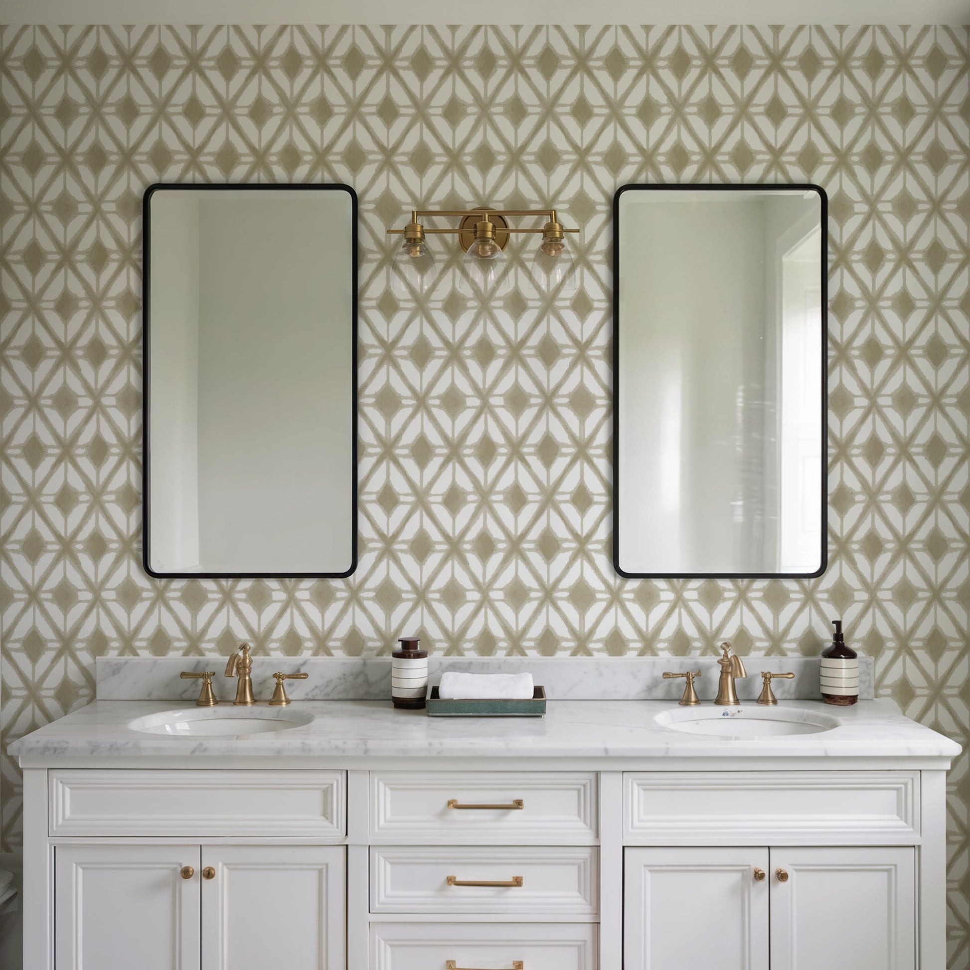White double-sink vanity with marble top, gold fixtures, two black-framed mirrors, beige geometric wallpaper, gold sconce.