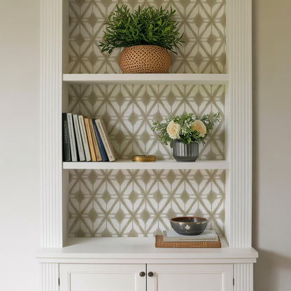 White built-in shelf with geometric wallpaper; top plant in woven basket, middle books and gray vase with cream roses, bottom black bowl.