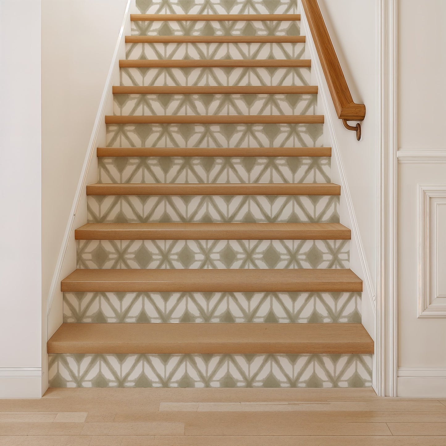 Oak staircase with light brown treads and white risers, geometric gray wallpaper, and a wooden handrail on the right.