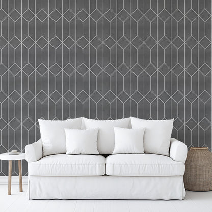 White sofa with four white cushions against charcoal geometric wallpaper; round side table and woven basket.