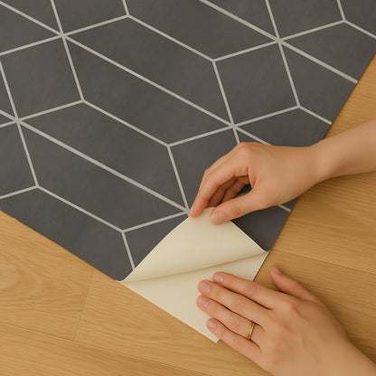 Dark gray wallpaper with white geometric hex shapes, being peeled back to reveal light backing; hands with ring.
