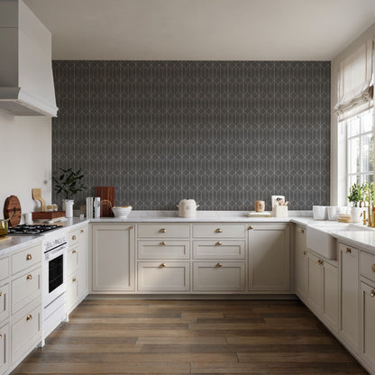 White shaker kitchen with brass hardware, dark geometric backsplash, wood floors, stove on left and windowed counter space.