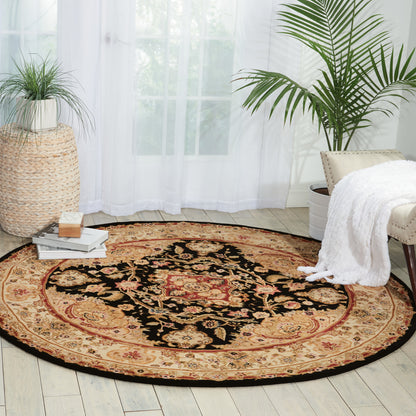 Round oriental rug with black center, red medallion and gold floral details on a beige border in a bright living room.