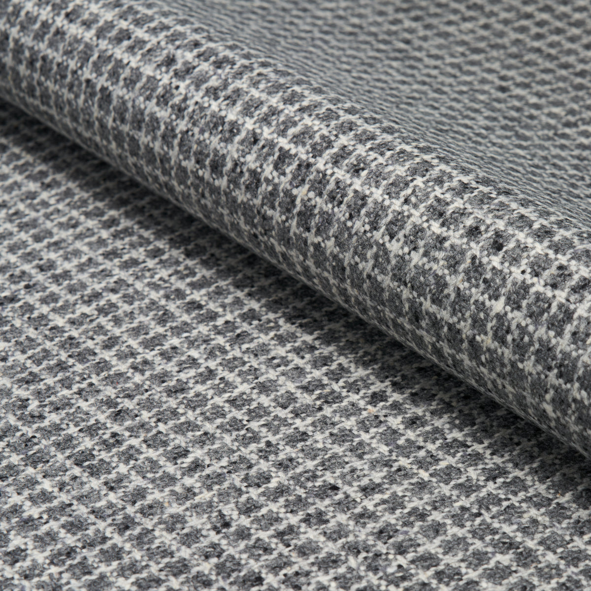 Gray and white houndstooth wool fabric rolled, textured weave ideal for suits, coats, or upholstery.