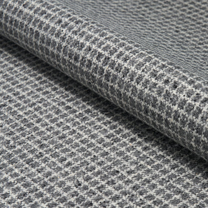 Gray and white houndstooth wool fabric rolled, textured weave ideal for suits, coats, or upholstery.