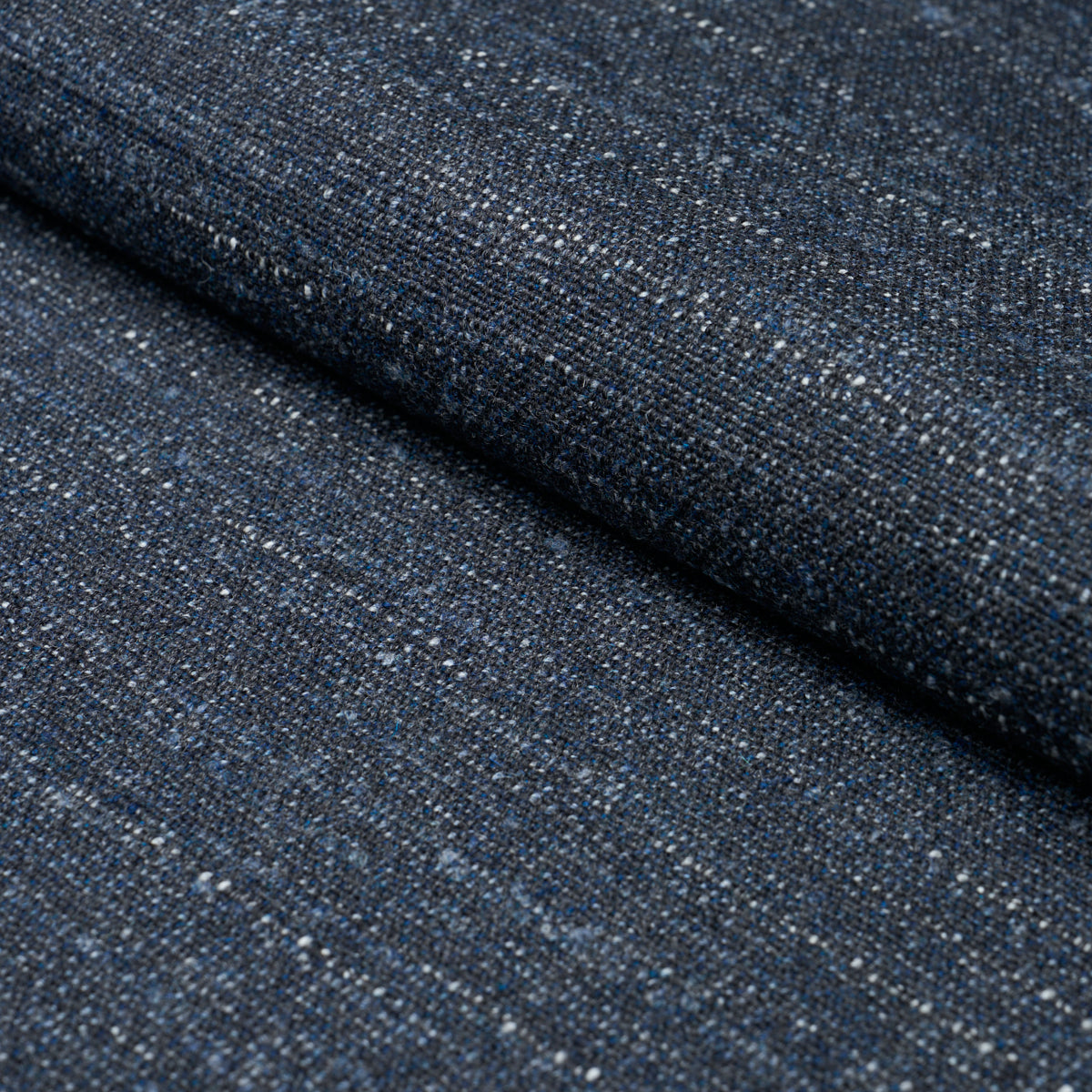 Dark indigo denim fabric with white flecks, folded to show textured twill.