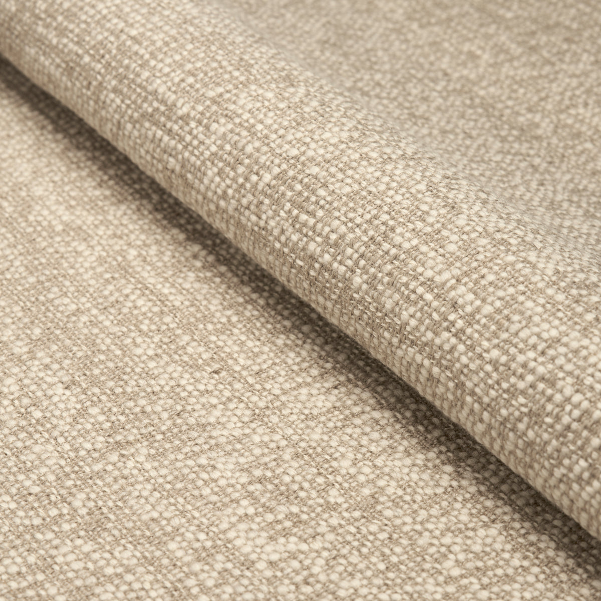 Beige woven fabric with coarse linen-like texture, rolled edge, ideal for upholstery or drapery.