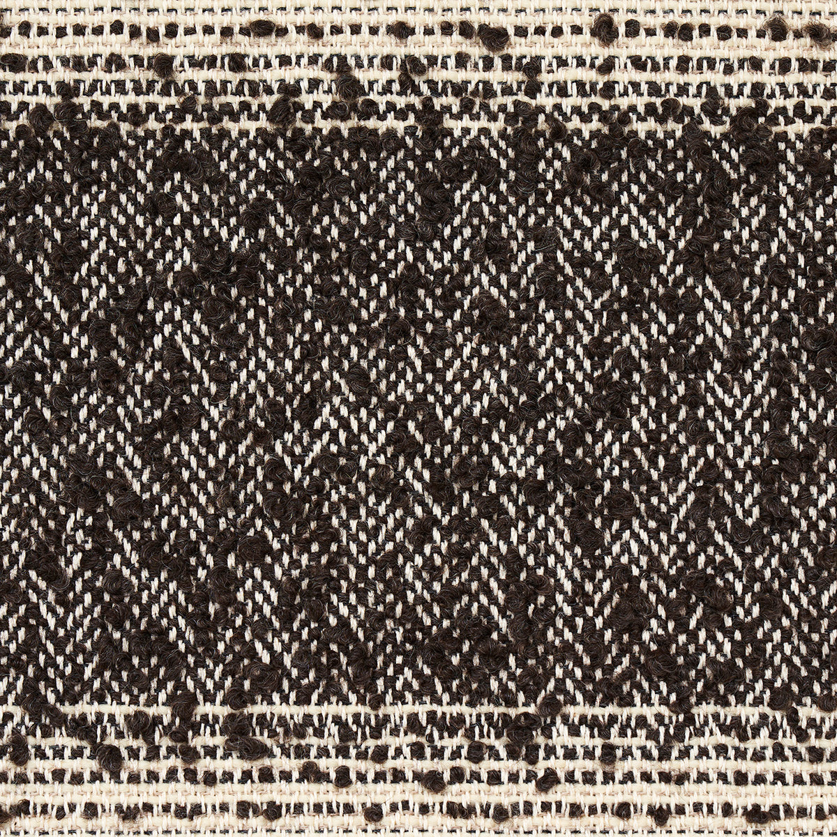 Close-up of black and ivory woven textile with diamond lattice pattern and cream border, rustic boho style.