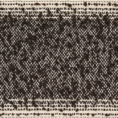 Close-up of black and ivory woven textile with diamond lattice pattern and cream border, rustic boho style.