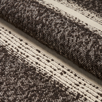 Dark brown and cream woven rug rolled up, with a textured striped pattern for rustic home decor.