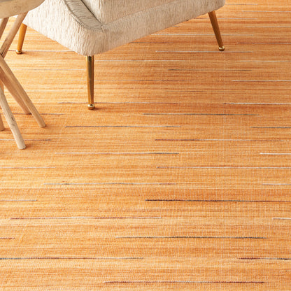 Beige fabric armchair with metal legs on an orange striped area rug.