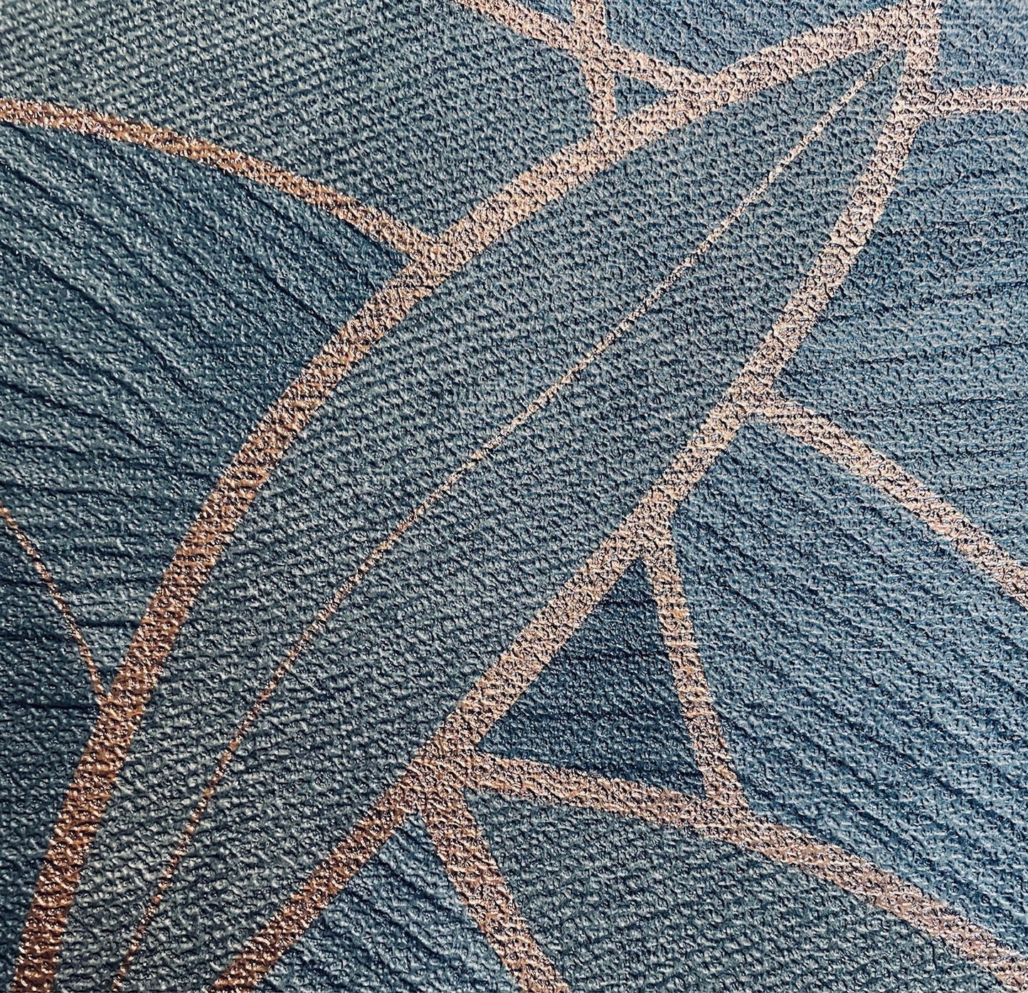 Close-up of dark moss green wallpaper with a carved leaf motif and subtle textured surface.