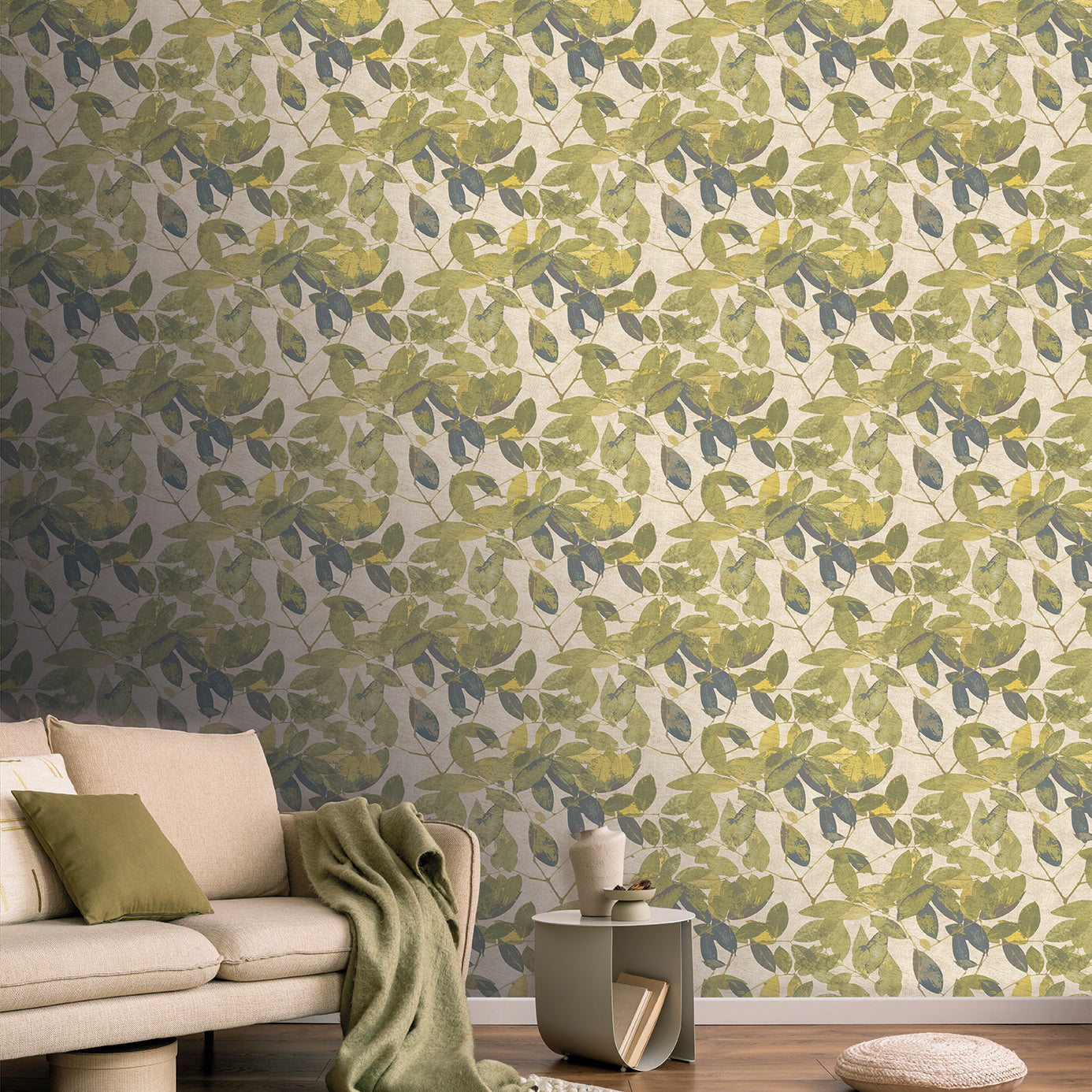 Cozy living room with leafy golden-green wallpaper, beige sofa with green cushions, green throw, wood floor and end table.