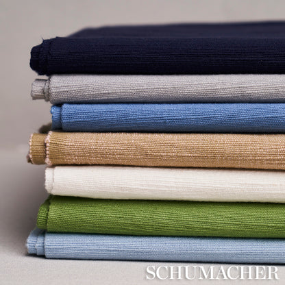 Stack of folded woven fabrics in navy, gray, light blue, beige, white, sage green, and sky blue.