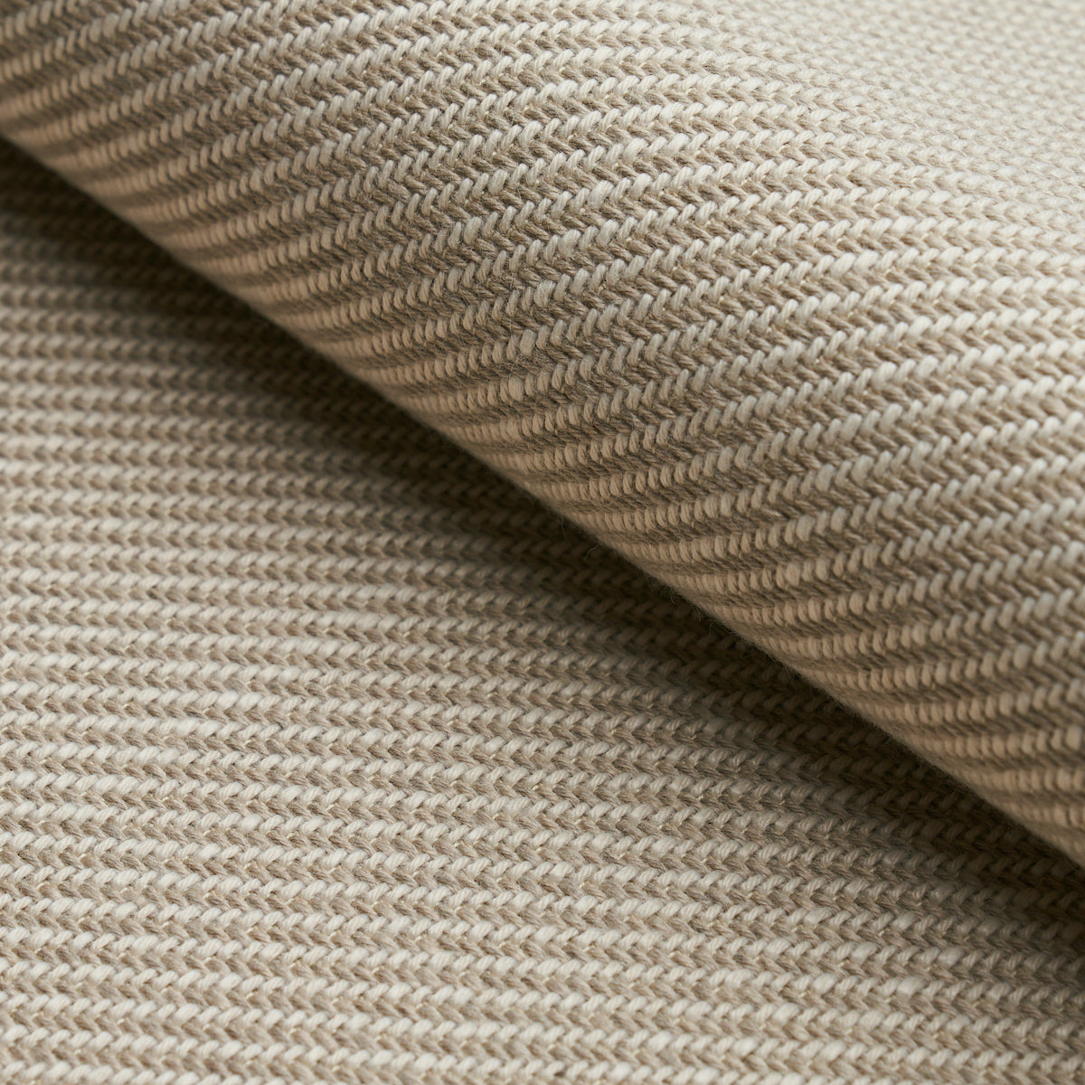 Close-up of beige woven fabric with a diagonal rib texture and a soft fold.