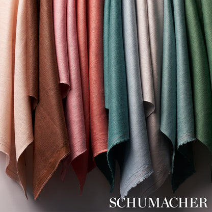 Rows of suede-like fabric swatches hanging side by side in warm to cool tones with fringed edges; Schumacher watermark.