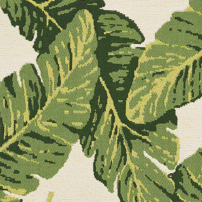 Botanical tapestry fabric with large green tropical leaves on beige background; woven texture