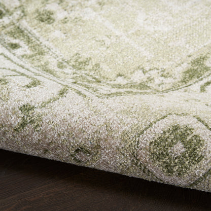 Olive green and beige oriental rug with medallion motif, thick plush pile, partially rolled edge on dark wood floor.