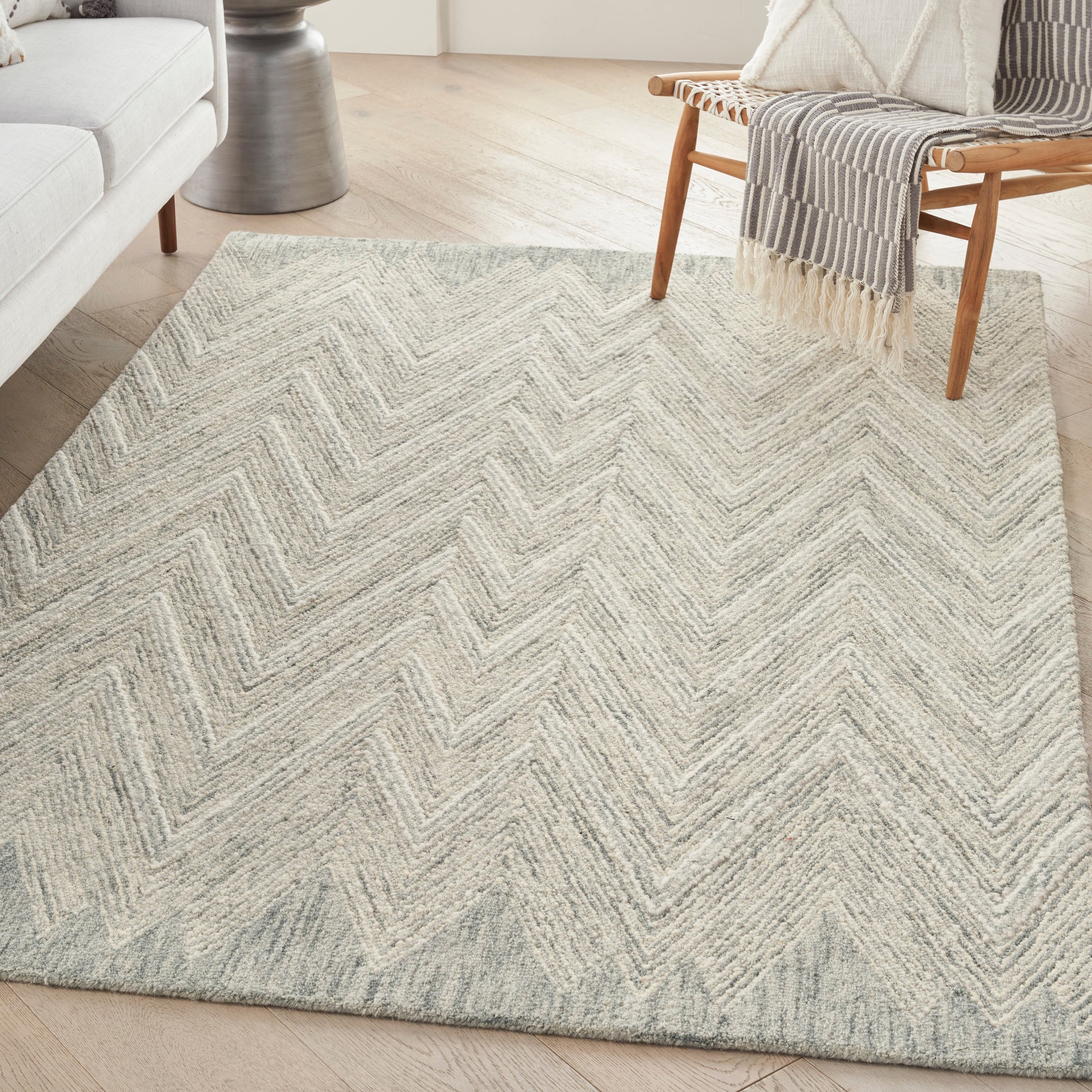 Rectangular woven area rug in light gray and cream chevron pattern, soft textured, for a modern living room.