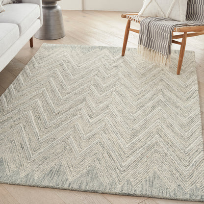 Rectangular woven area rug in light gray and cream chevron pattern, soft textured, for a modern living room.