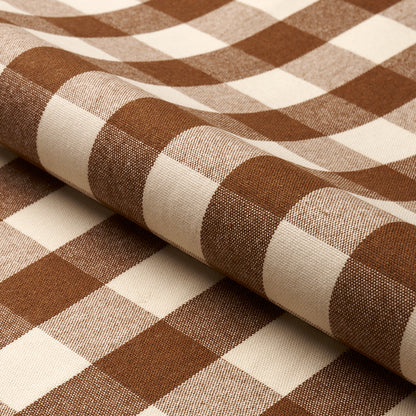 Brown and cream gingham cotton fabric, folded to reveal bold checked pattern; ideal for shirts or table linens.