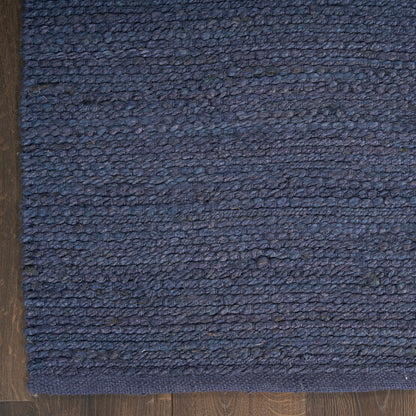 Dark blue loop-pile rug on wood floor with navy woven texture and bound edge.