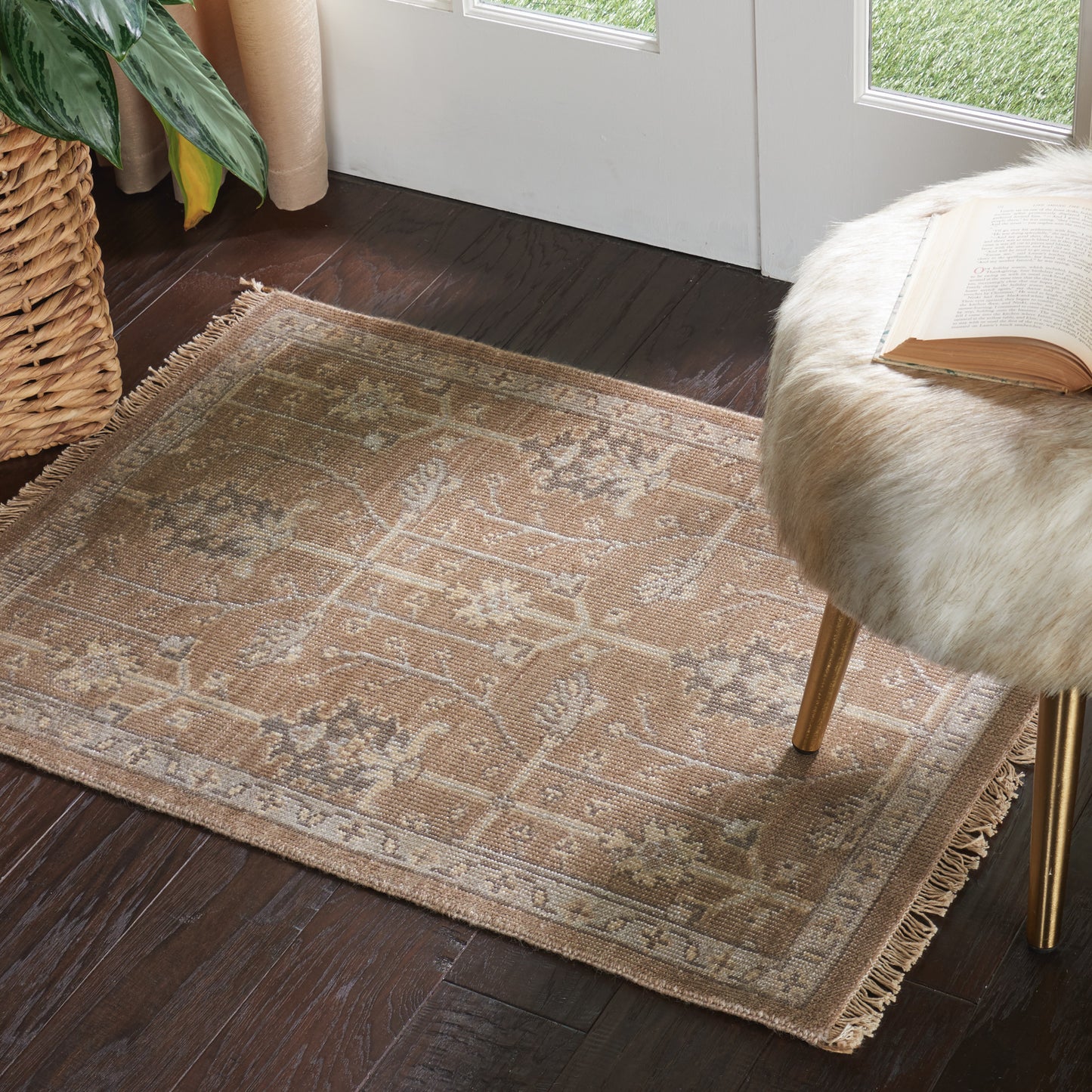 Beige patterned area rug on dark wood floor beside glass doors, with a fur-covered stool and an open book.