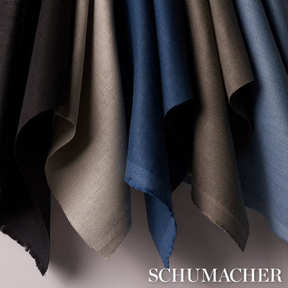 Hanging fabric swatches in black, beige, gray, and blue with textured weaves; draped edges, Schumacher branding.