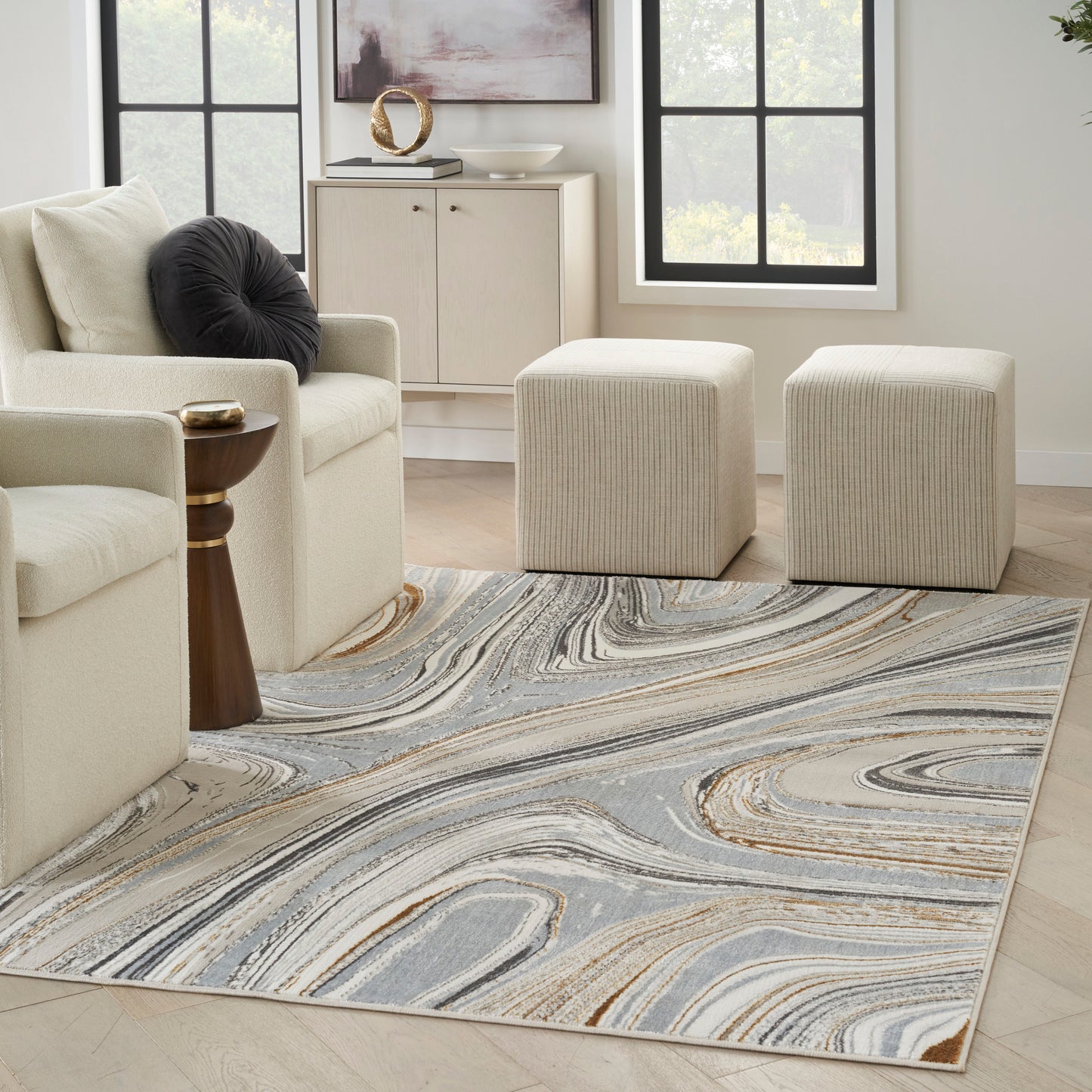 Contemporary abstract swirl area rug in gray, beige, and tan tones; soft plush pile under cream living room seating.