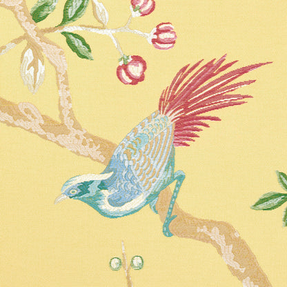 Blue-green bird with maroon tail perched on a branch with green leaves and red berries on yellow fabric pattern.