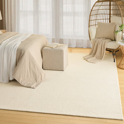 Bedroom with beige duvet on bed, cream area rug, light wood floor, wicker hanging chair, neutral cushions, cozy throw.
