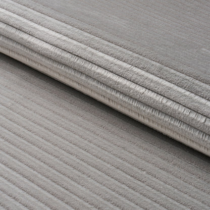 Grey ribbed rug, rolled up, showing soft plush pile and textured stripes.