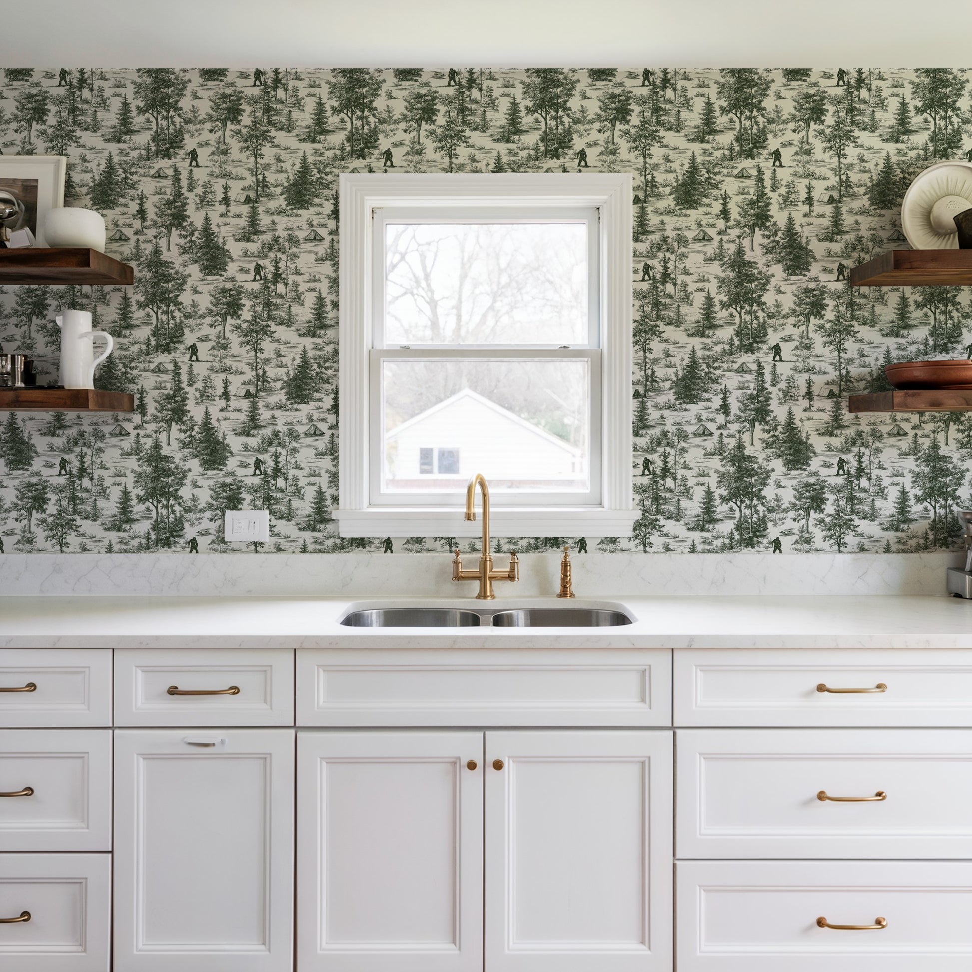 White kitchen with forest wallpaper, brass faucet, double sink, white cabinetry, and open wooden shelves.