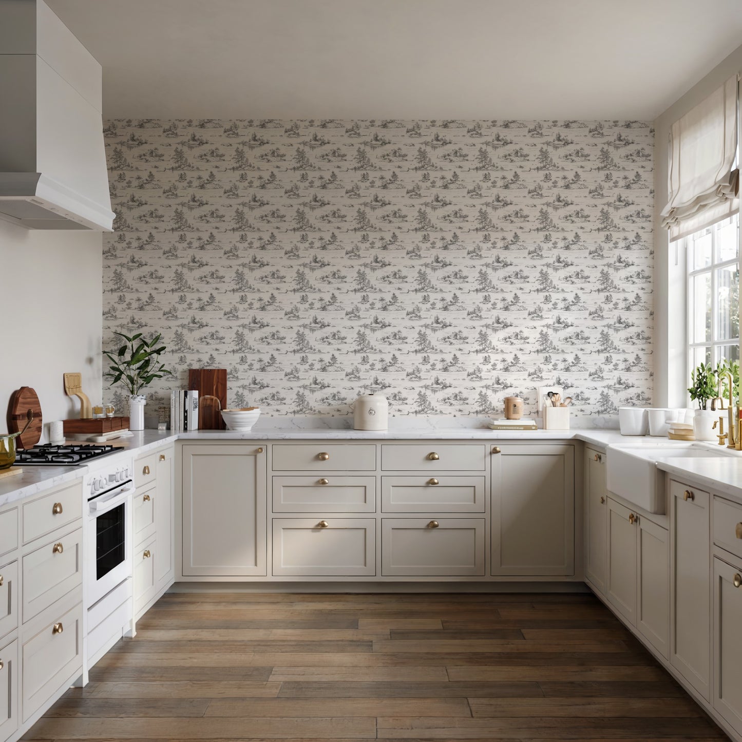 Cream shaker kitchen with brass hardware, toile wallpaper, white countertops, and dark wood floor; gas range and hood.