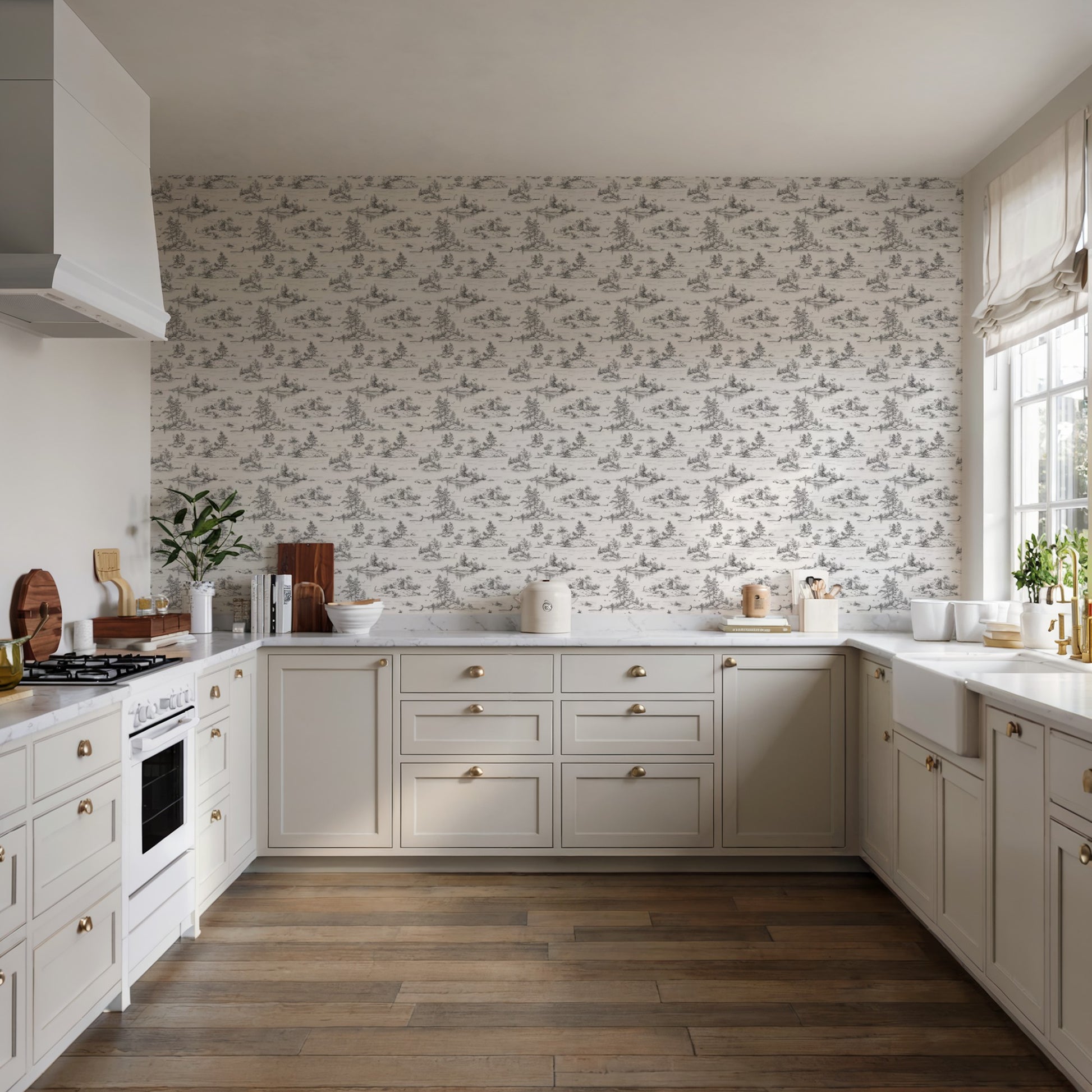 Cream shaker kitchen with brass hardware, toile wallpaper, white countertops, and dark wood floor; gas range and hood.
