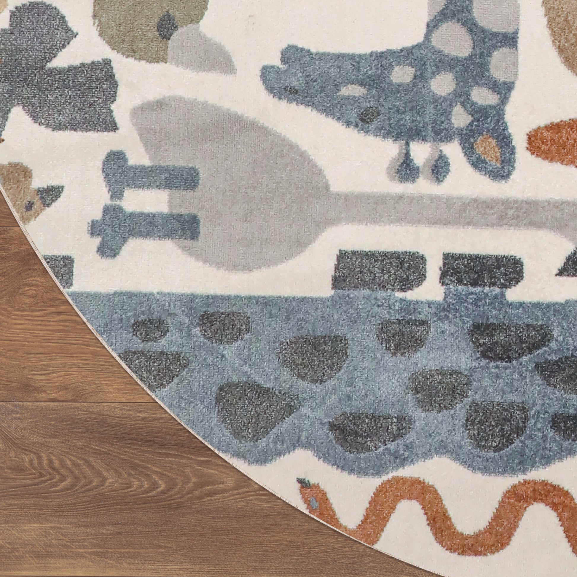 Round rug on wood floor with cream background, blue-gray shapes and orange squiggle, modern playful design.