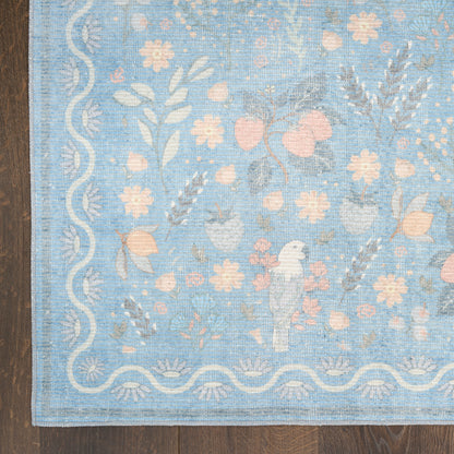 Blue woven area rug with pale pink flowers and white scalloped border on a wooden floor.