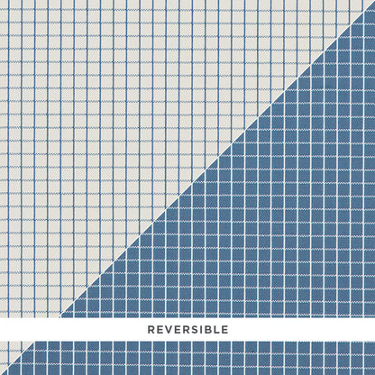 Reversible grid-pattern rug with pale white on one side and deep blue on the other, diagonal seam.